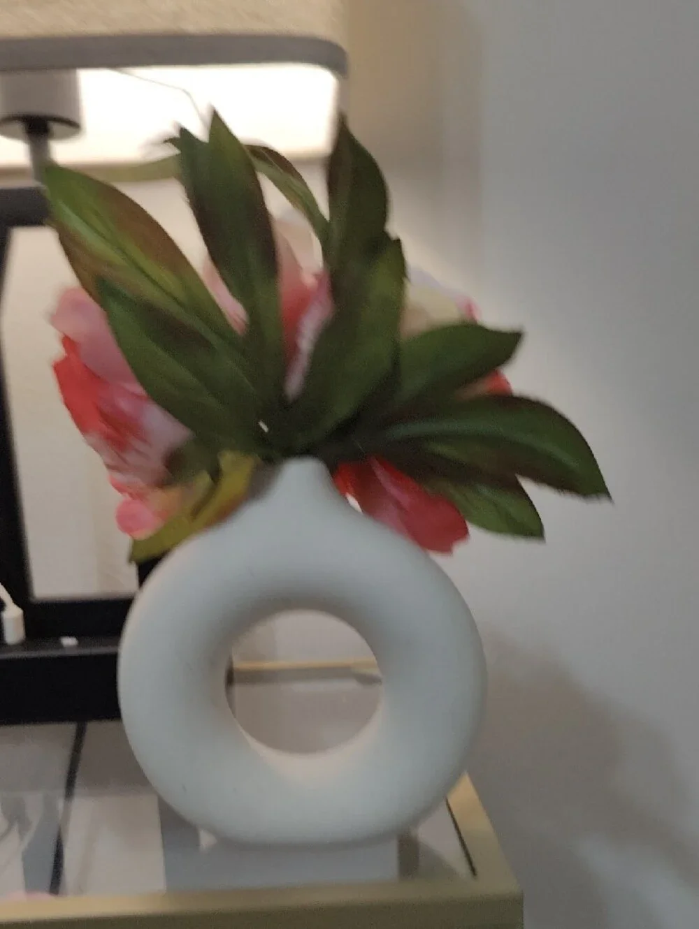 White Donut Ceramic Vase with Beautiful Pink Peony Flowers and Green Leaves.